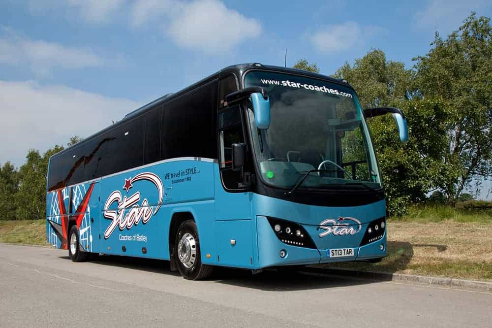 Blue "Star" coach bus on road, Panther OS6 model, with trees in background.