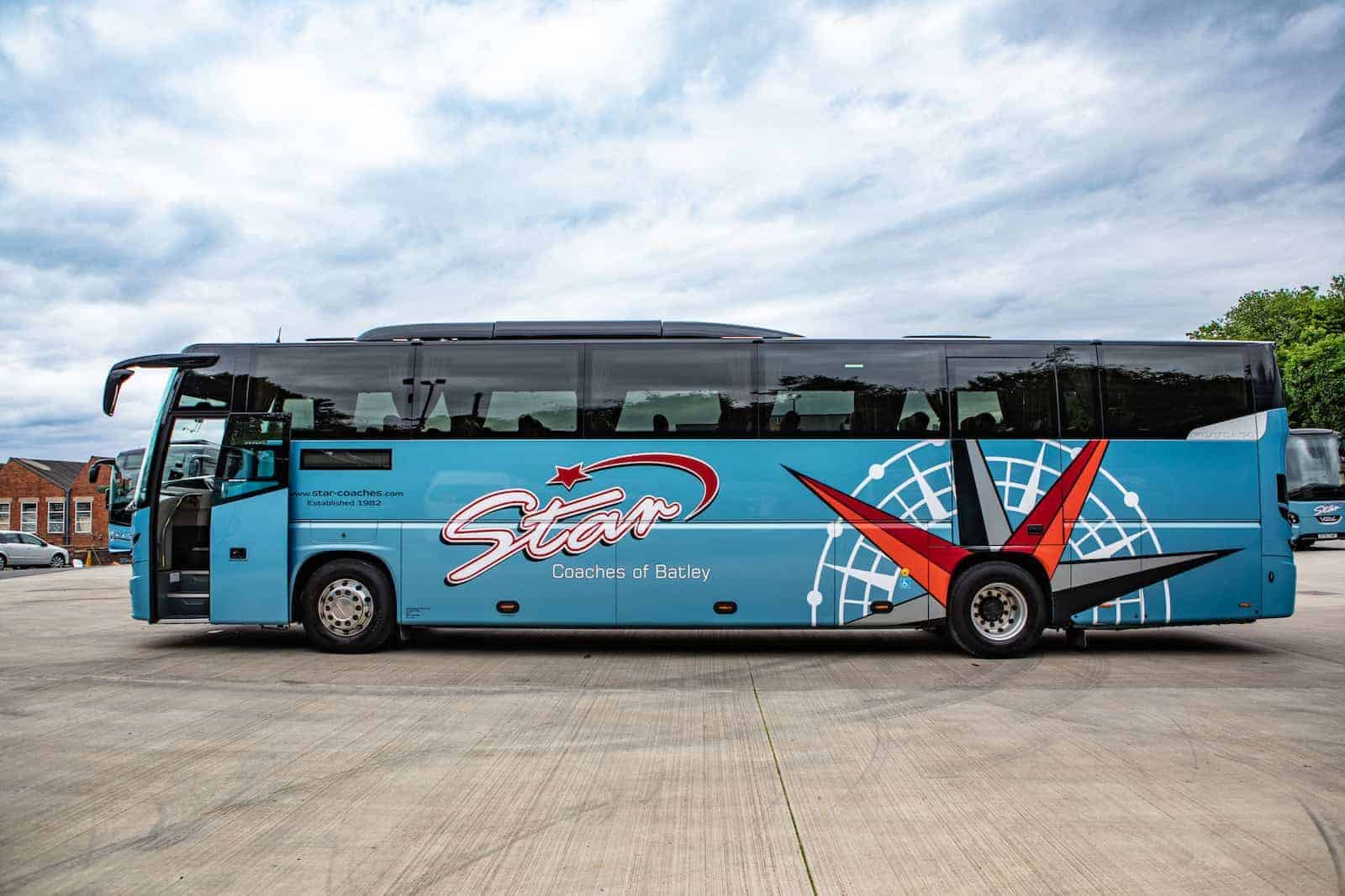 A blue coach bus with "Star Coaches of Batley" branding parked; illustrating coach vs taxi concept.